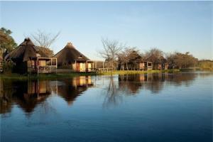 a group of huts sitting on top of a lake at Camp Kwando in Kongola