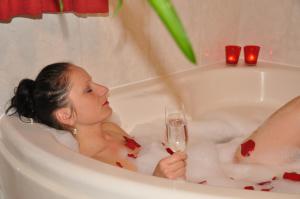 Eine Frau, die in einer Badewanne sitzt und ein Glas Wein hält. in der Unterkunft Appartementhaus Grill in Strobl