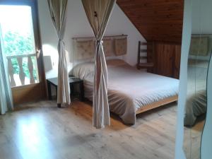um quarto com uma cama com cortinas e uma janela em Chambres d 'hôtes "Au vieux Préssoir" em Belley