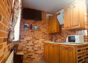 a kitchen with wooden cabinets and a brick wall at Zolotoi Bereg 31 in Odesa