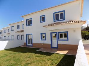 une grande maison blanche avec des portes bleues et une cour dans l'établissement Casa Foz, à Foz do Arelho