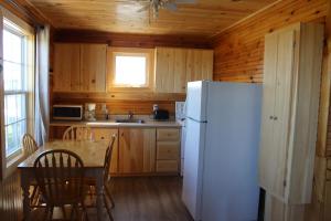 cocina con nevera blanca y mesa en Chalets Grand Pre Cottages en North Rustico