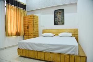 a bedroom with a wooden bed with white sheets at Nutz Backpackers in Amritsar