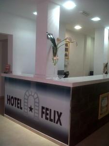 un mostrador de recepción del hotel con un jarrón de flores. en Hotel Felix, en Lorca