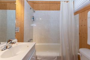 y baño con bañera, lavamanos y ducha. en Motel au Fleuve d'Argent, en Rivière-du-Loup