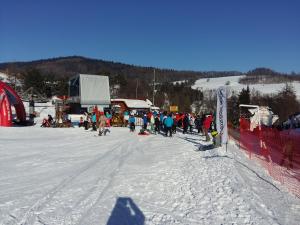 un groupe de personnes debout dans la neige sur une piste de ski dans l'établissement Domek 87, à Krynica-Zdrój