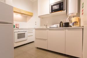 a kitchen with white cabinets and a microwave at Alfama Tailor Made Blue House With a View #1 in Lisbon