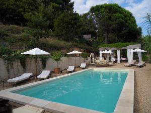a swimming pool with chairs and umbrellas at La Maison d'Allouma in La Garde-Freinet