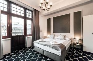 a bedroom with a bed with a chandelier and windows at Apartamenty L5 in Krakow