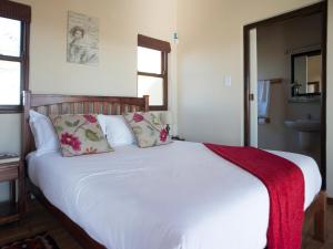 a bedroom with a white bed with a red blanket on it at Wild Clover Cottages in Stellenbosch