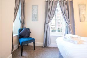 1 dormitorio con una silla azul frente a una ventana en The Royal Oak Pub en Lampeter