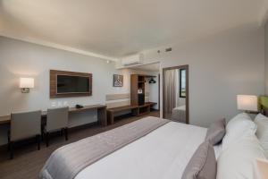 a bedroom with a bed and a desk and a television at Linx Confins in Confins