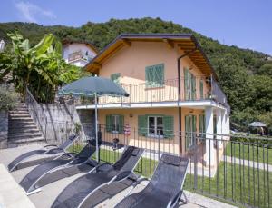 - un groupe de chaises et un parasol devant une maison dans l'établissement Montagna del Sole, à Dizzasco