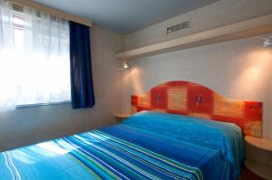 sypialnia z łóżkiem z drewnianym zagłówkiem i oknem w obiekcie Villaggio Azzurra w mieście Termoli