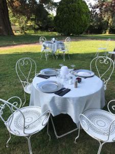 ein weißer Tisch mit Stühlen und ein Tisch mit Tellern darauf in der Unterkunft Chateau de Breuil en Beaujolais in Salles-Arbuissonnas