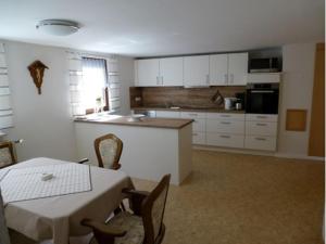 a kitchen with white cabinets and a table and a table and chairs at Ferienwohnung Haßmüller in Sulzdorf an der Lederhecke