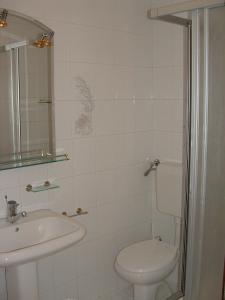 a white bathroom with a toilet and a sink at Apartments Mladina in Mimice