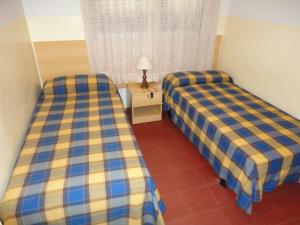 a room with two beds and a table with a lamp at Lamoga Ona in Torredembarra