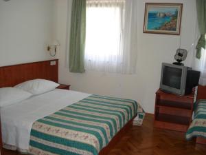 a hotel room with a bed and a tv at Apartments Mladina in Mimice