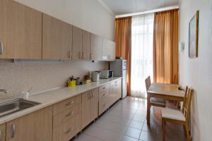 una cocina con armarios de madera, mesa y fregadero en Hotel Aviator, en Ufa
