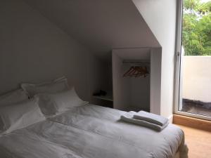 a white bed in a room with a window at Trafaria Garden Beach Houses in Trafaria