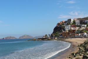 a beach with buildings on a hill next to the ocean at Casa de Leyendas in Mazatlán