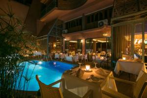 Le Caspien Boutique Hotel في مراكش: مطعم فيه مسبح وطاولات وكراسي