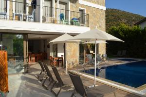 un patio con sillas y sombrillas junto a una piscina en Aria Doria Otel en Datca