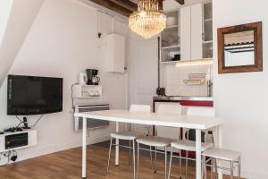 een witte eetkamer met een witte tafel en stoelen bij Charming 30m² border of MONTMARTRE in Parijs