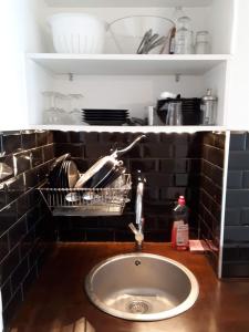 a sink in a kitchen with a black tiled wall at Cosy 30m² DENFERT-ROCHEREAU district in Paris