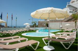um grupo de cadeiras e um guarda-sol junto a uma piscina em Montesol Atsol em Puerto Rico de Gran Canaria