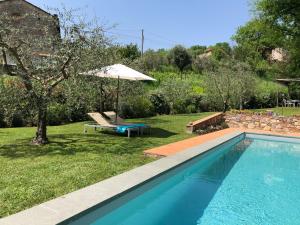 een zwembad in een tuin met een parasol en een bank bij La Casa Toscane in Capannori