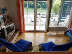 un soggiorno con 2 sedie blu e una TV di Apartment Lent a Maribor