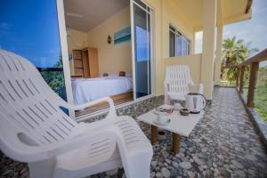 ソドゥーにあるRelax Residence Thoddoo Maldivesの白い椅子2脚とベッド1台が備わる客室です。