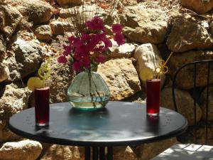 un jarrón con flores en una mesa con dos vasos en Casa el Chorro en El Chorro