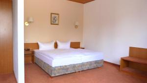 a bedroom with a bed with white sheets and pillows at Hotel Mühlenhof in Heidenau