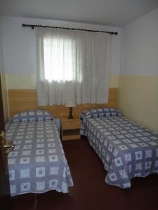 two beds in a hotel room with a window at Lamoga Ona in Torredembarra