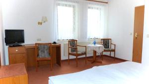 a room with a bed and a table and chairs at Hotel Mühlenhof in Heidenau