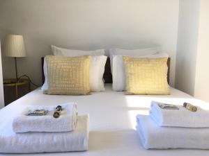 uma cama branca com toalhas e almofadas em Casa da Maria Alfama em Lisboa