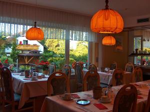 ein Esszimmer mit Tischen, Stühlen und Lampen in der Unterkunft Hotel Schmid in Bad Bellingen