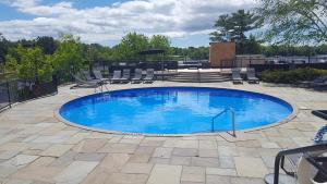 a large swimming pool with chairs and an umbrella at Taboo Muskoka in Gravenhurst