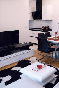 uma sala de estar com televisão e uma mesa com cadeiras em Green Diamond em Zagreb