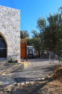 une voiture garée à côté d'un bâtiment en pierre avec une allée dans l'établissement Villa Marikami, à Kamilárion