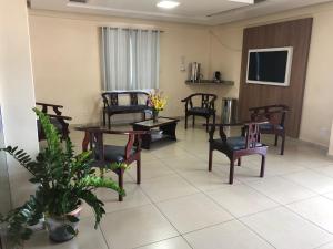 a waiting room with chairs and tables and a tv at Epílogo Palace Hotel in Rio Branco