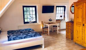 a bedroom with a bed and a desk and windows at Landhaus Schlunt in Wustrow