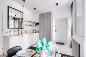 uma cozinha com armários brancos e uma mesa com uma planta em Marta Old Town Apartment em Varósvia