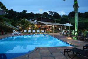 a large swimming pool with chairs and a restaurant at BellaMinas Pousada in Guapé