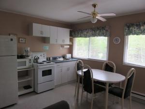 Cormack的住宿－Lush's Cottages，厨房配有桌子和白色冰箱。