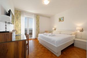 een slaapkamer met een wit bed en een groot raam bij Apartmens Villa Antonio 88 in Brela