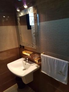 La salle de bains est pourvue d'un lavabo, d'un miroir et d'une serviette. dans l'établissement Select Hôtel, à Morondava